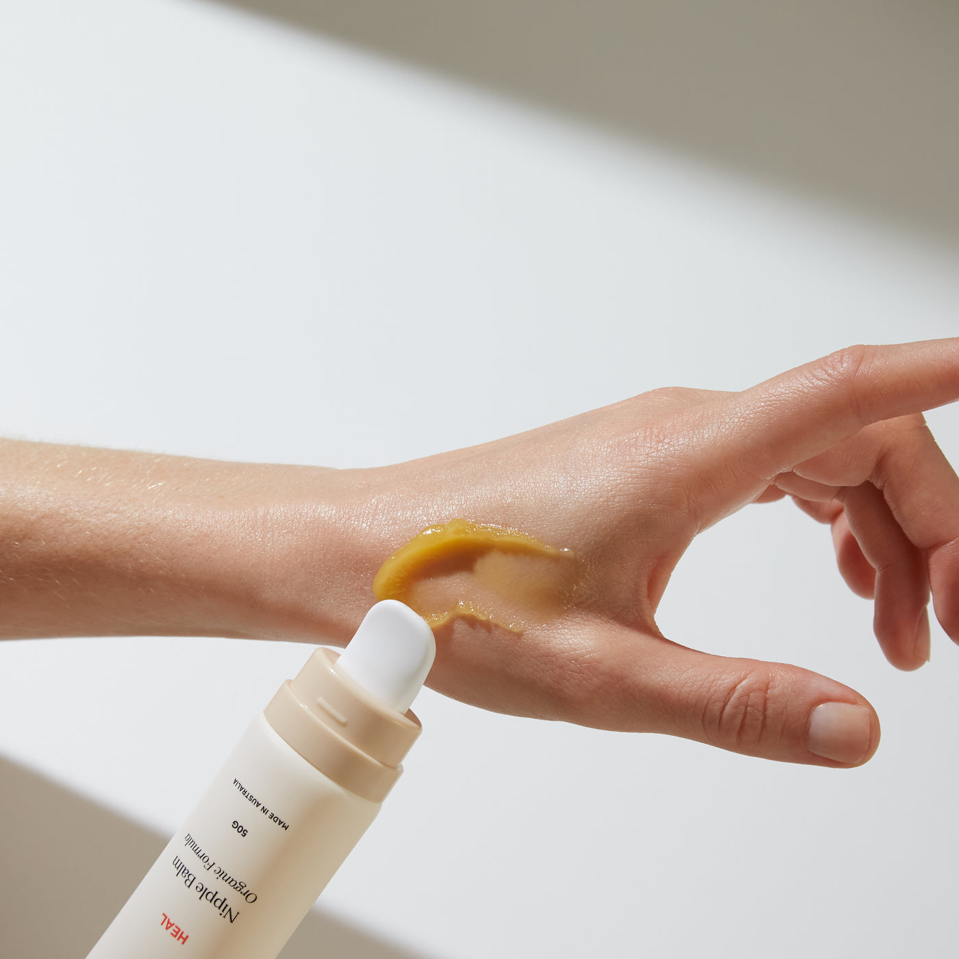 The maternity market, Hand shown with tube of bare mum nipple balm, cap has been removed and balm has been spread across back of thumb