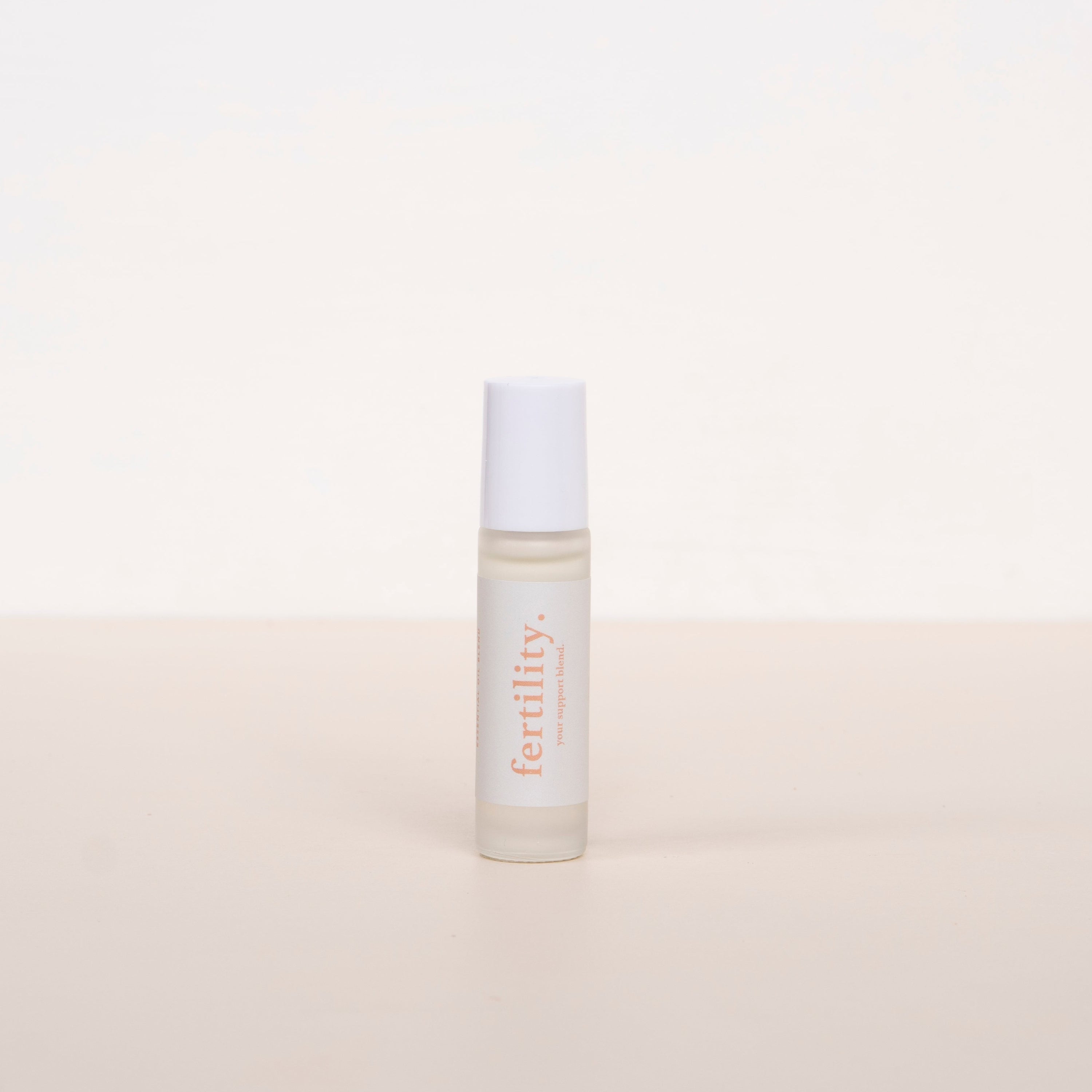Cle naturals fertility essential oil roller standing upright against neutral background 