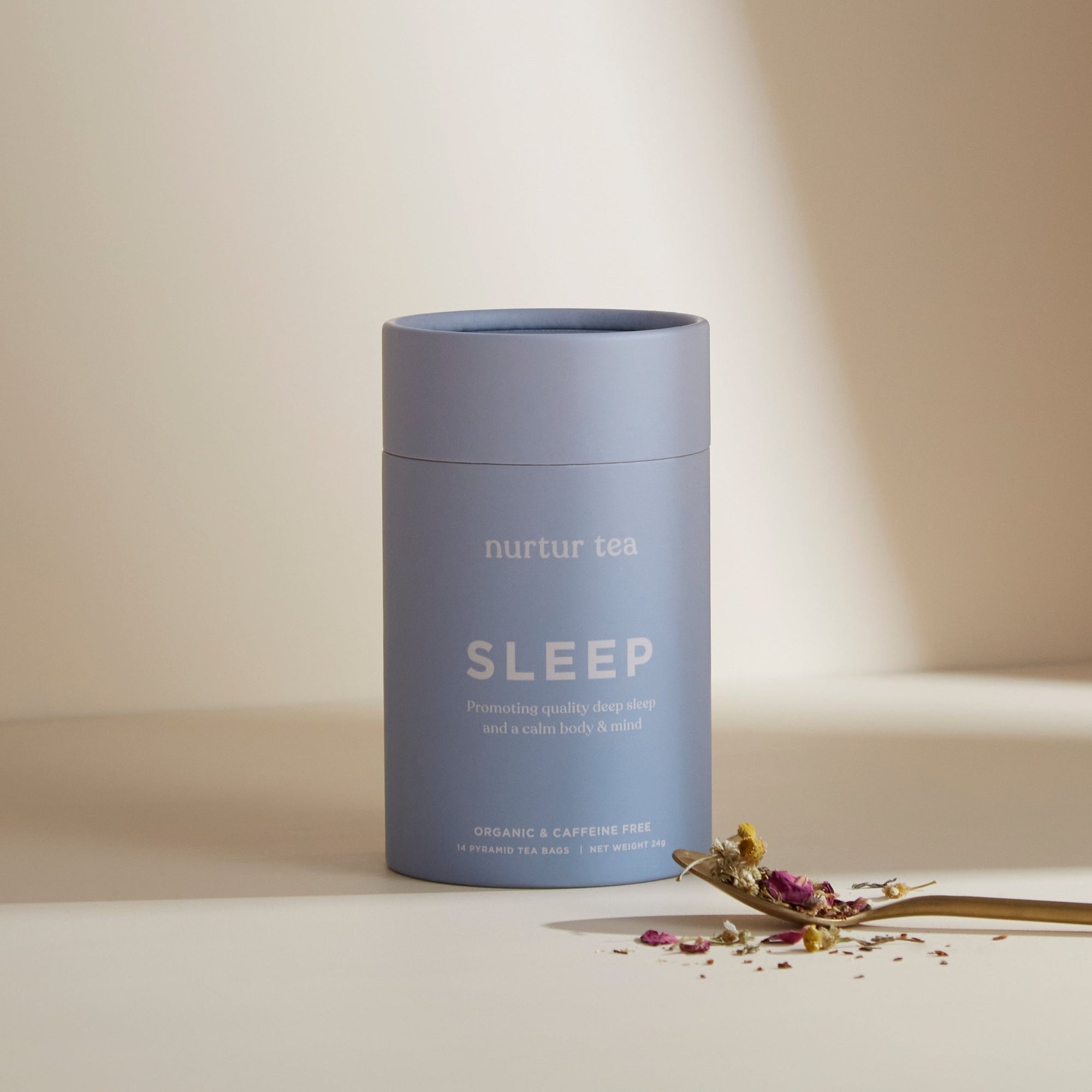 Love Tea, Nurtur Tea Sleep blend canister, blue canister with neutral background, some loose leaf tea sitting on gold spoon just in front of packaging
