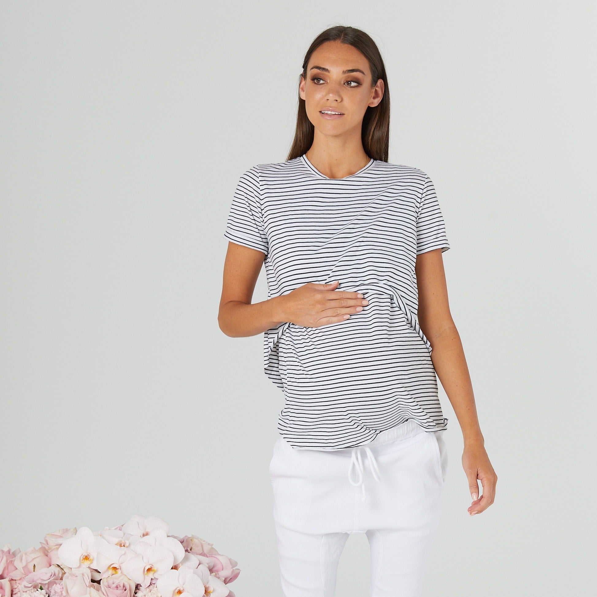 Pregnant model wearing valance II tee resting one arm on her belly, white tea with navy stripes across it